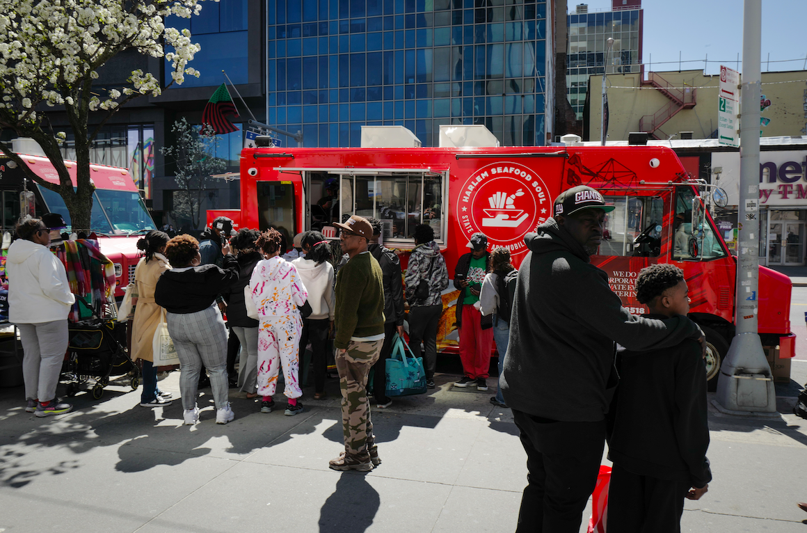 People waiting in line outside of the Harlem Seafood Soul food truck